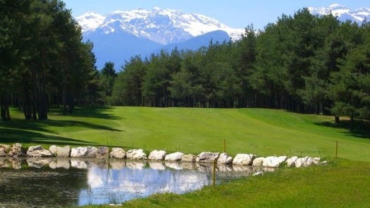 scorcio di un fairway del golf club Dolomiti. In primo piano un ostacolo d'acqua, sullo sfondo una montagna del Trentino